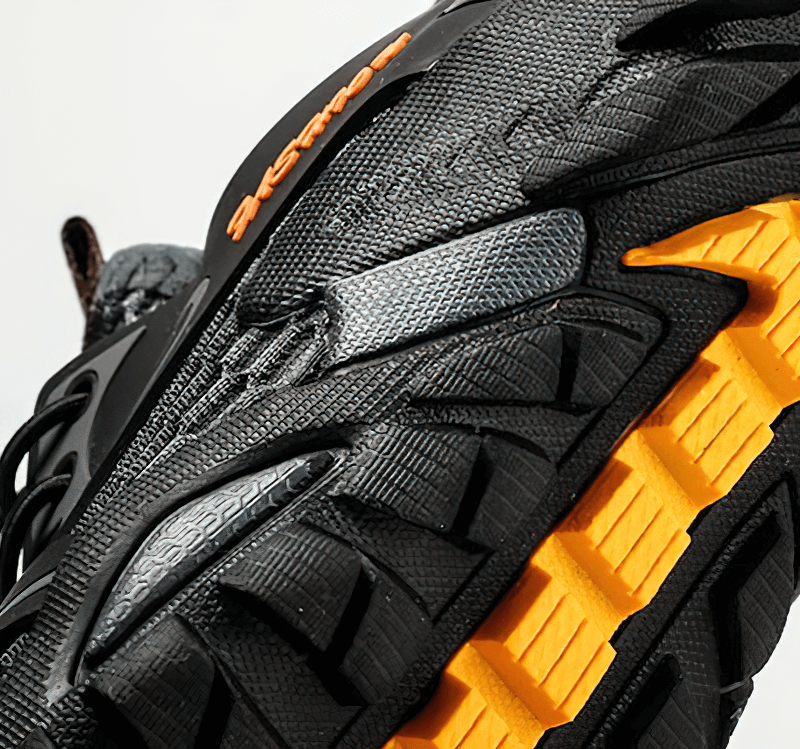 Close-up of rugged outsole on men's waterproof non-slip hiking sneaker with black and orange detail.
