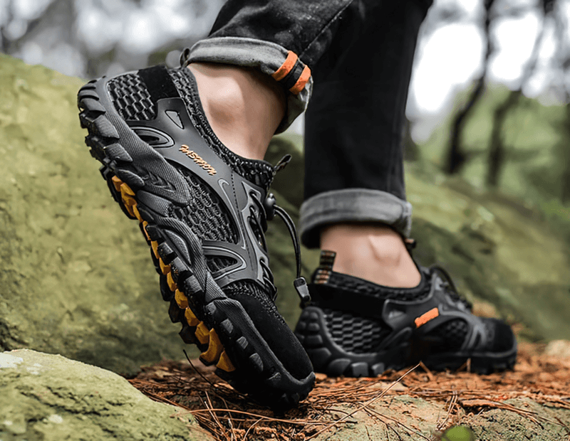 Man wearing waterproof non-slip climbing sneakers SF0579 on rugged terrain, showcasing superior traction and stylish design.