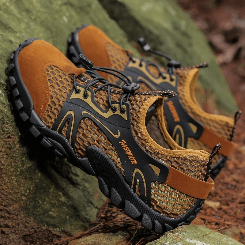 Stylish waterproof non-slip climbing sneakers for men, perfect for hiking with air mesh and PU leather, on a rocky terrain.