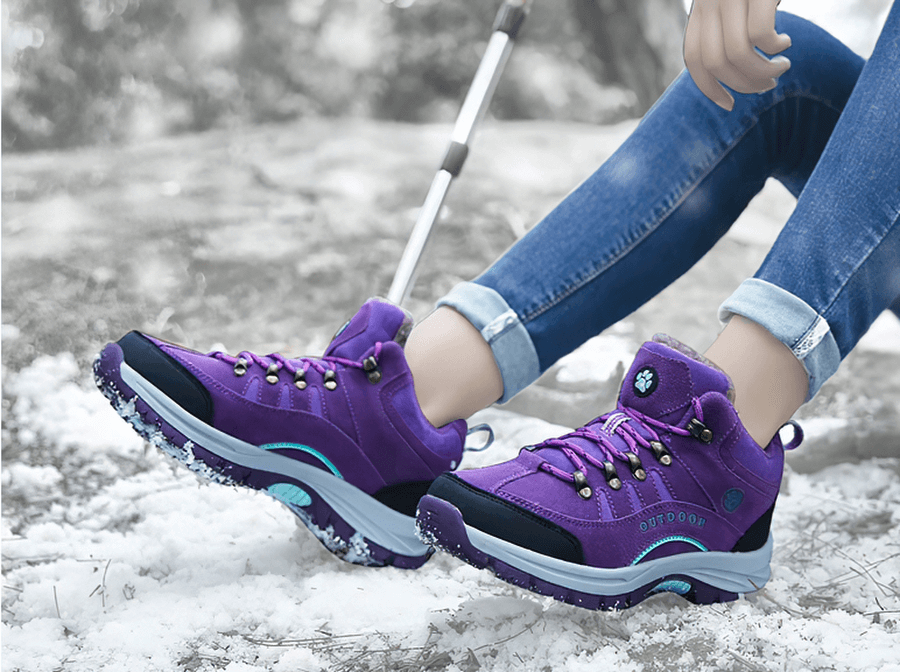 Person wearing waterproof snow trekking boots with anti-collision toe, purple suede uppers, and rubber outsoles perfect for winter hikes.