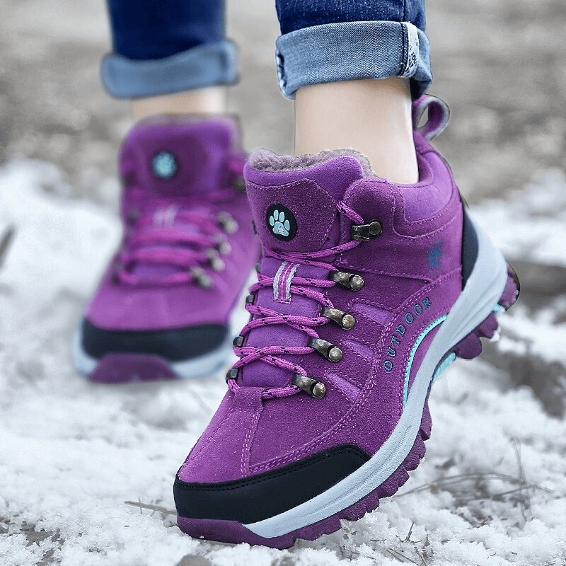 Person wearing waterproof snow trekking boots with anti-collision toe in purple, perfect for outdoor adventures in snow.