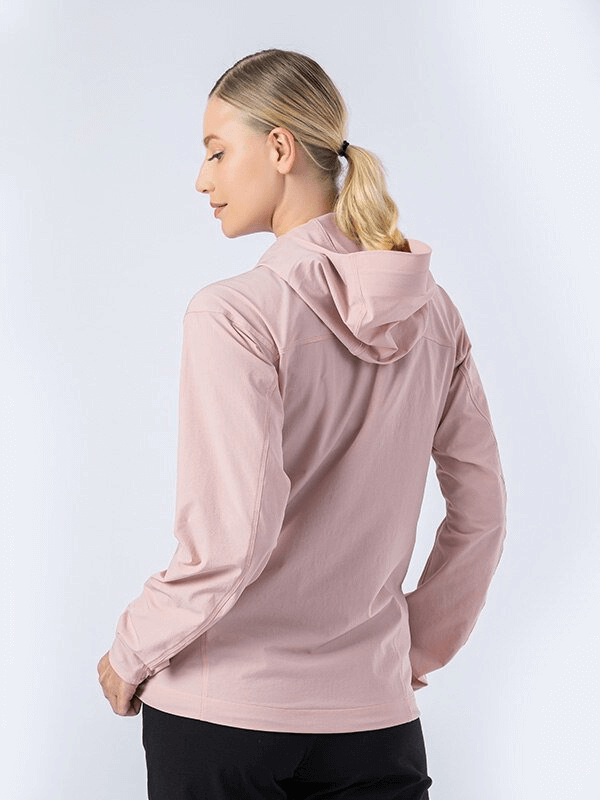Woman wearing pink waterproof sports jacket with hood, perfect for running. Lightweight and breathable design.