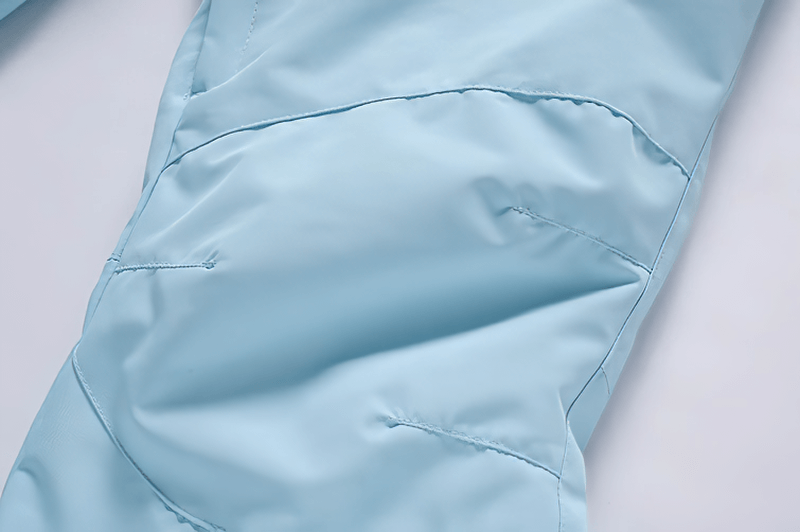 Close-up of light blue waterproof snowboarding trousers showing durable fabric and stitching.