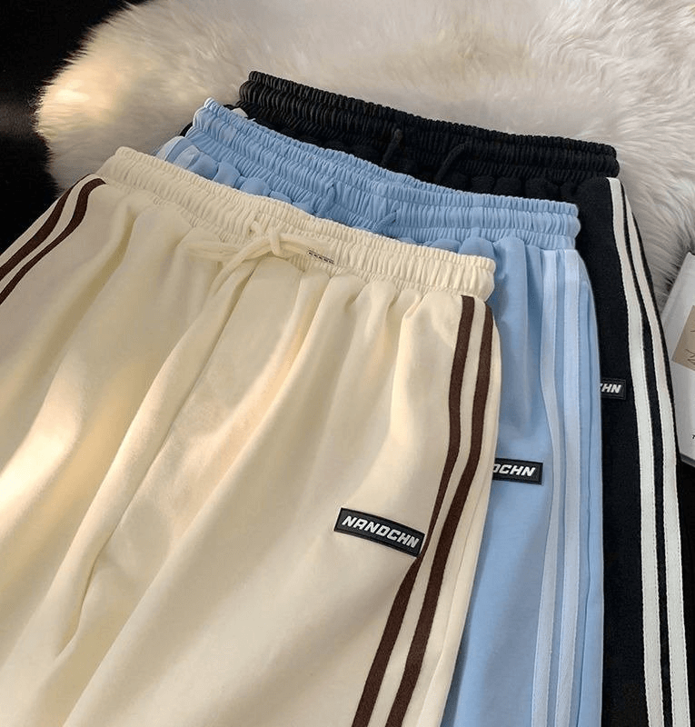 Stack of women's wide sport casual shorts in cream, blue, and black with elastic waistband, perfect for active wear.