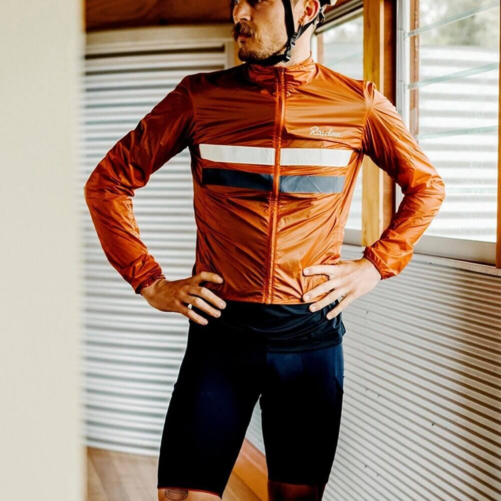 Unisex windproof cycling jacket in orange with reflective features, full zipper, perfect for safe and comfortable rides.