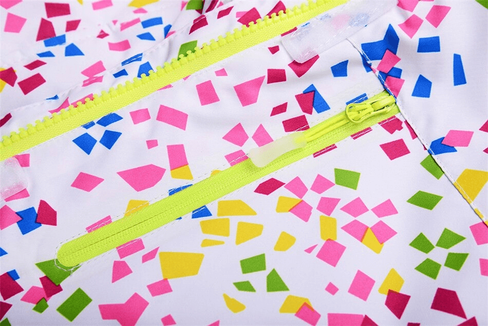 Close-up of colorful pattern on a windproof skiing jacket with yellow zippers, showcasing vibrant pink, green, and blue geometric shapes.
