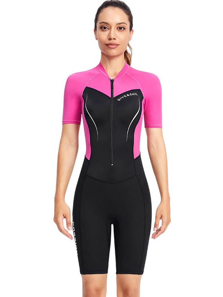 Woman wearing a pink and black 1.5mm neoprene wetsuit for surfing and diving, designed for warmth and protection. Perfect for water sports.