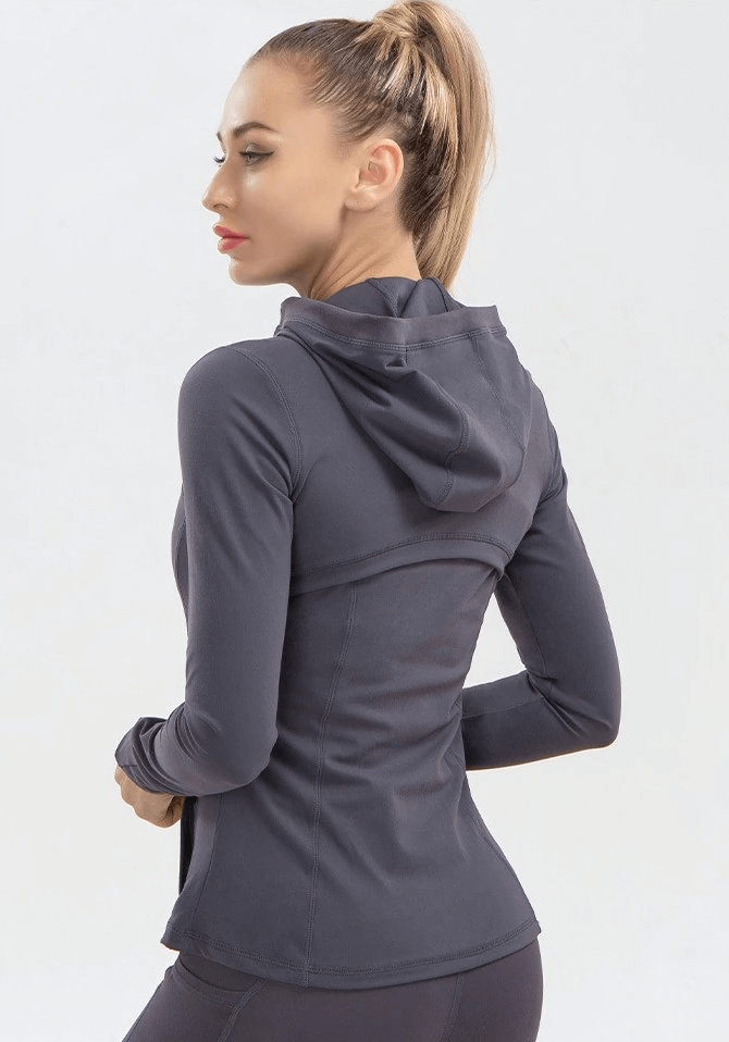 Woman wearing a long-sleeve quick-drying sports shirt for yoga, showing back view with hoodie, in a sleek dark color.