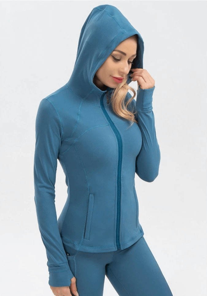 Woman wearing a blue long-sleeved sports shirt, quick-drying, perfect for yoga, with hood, designed for comfort and movement.