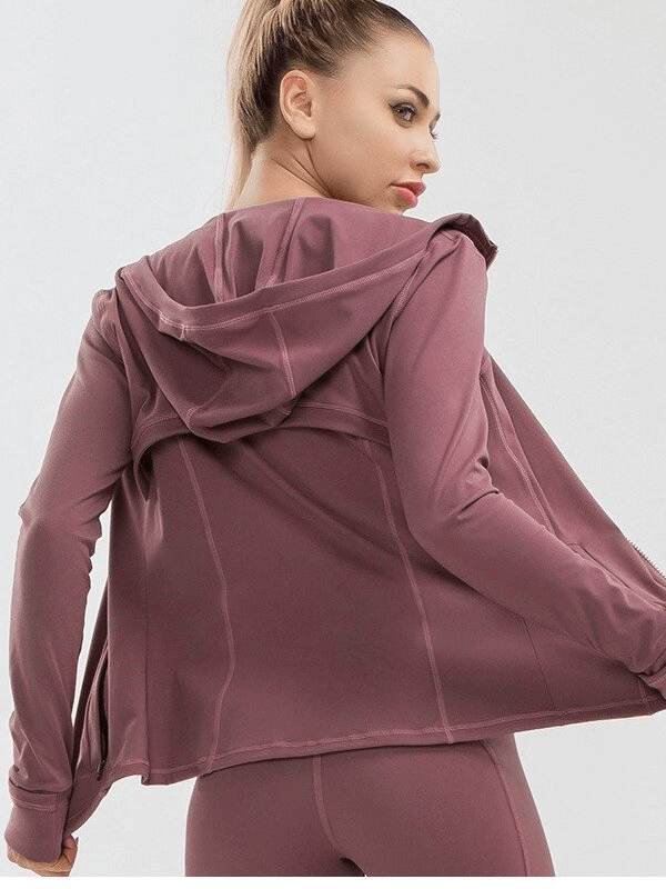 Woman wearing a long-sleeved quick-drying sports shirt in mauve, perfect for yoga, featuring a hoodie and four-way stretch fabric.