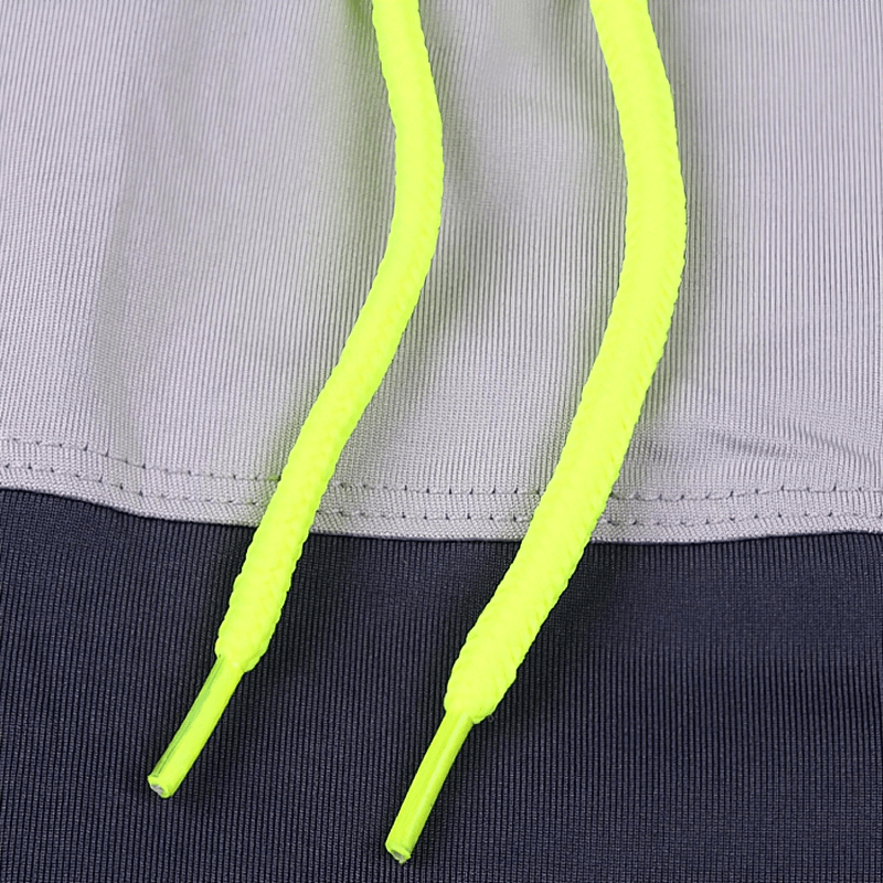 Neon yellow drawstrings on breathable polyester-spandex tennis skirt-shorts in deep gray with stylish contrast stitch.