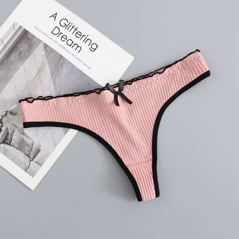 Pink low-rise T-back G-string cotton panties with black trim and bow, stylish women's lingerie on display.