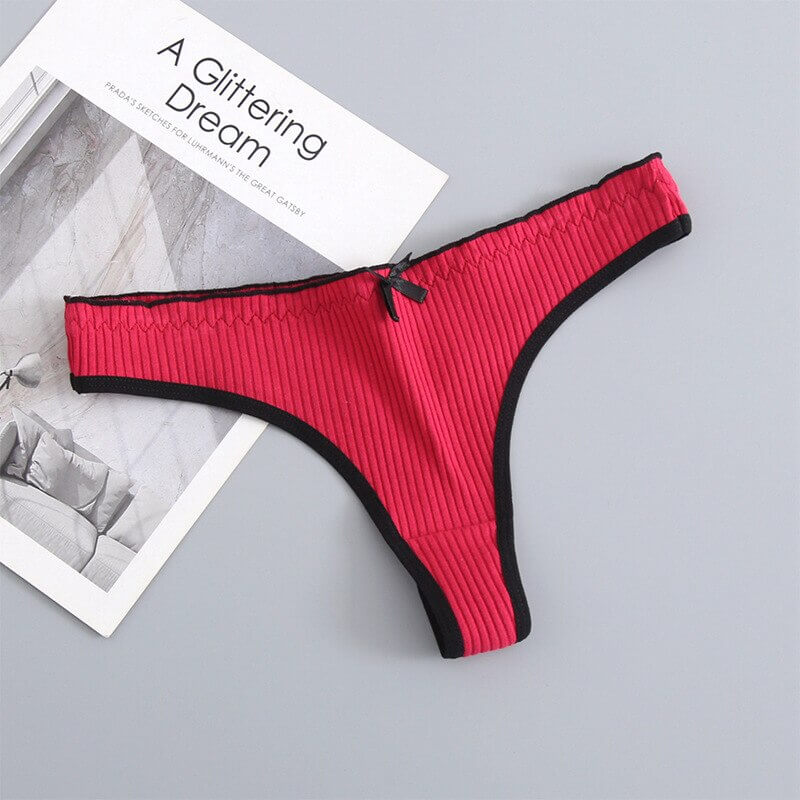 Red women's cotton low-rise T-back G-string panties with black trim and bow, displayed on a flat surface for an elegant look.