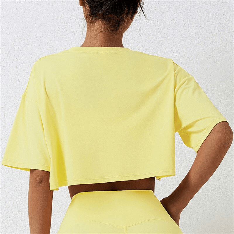 Back view of a yellow cropped loose sports t-shirt with short sleeves, perfect for active women seeking a comfortable and stylish fit.