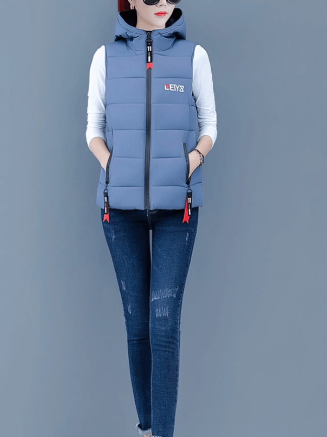 Stylish women's down vest with zipper pockets, hooded collar, and zippered closure for warmth and comfort in cooler temperatures.