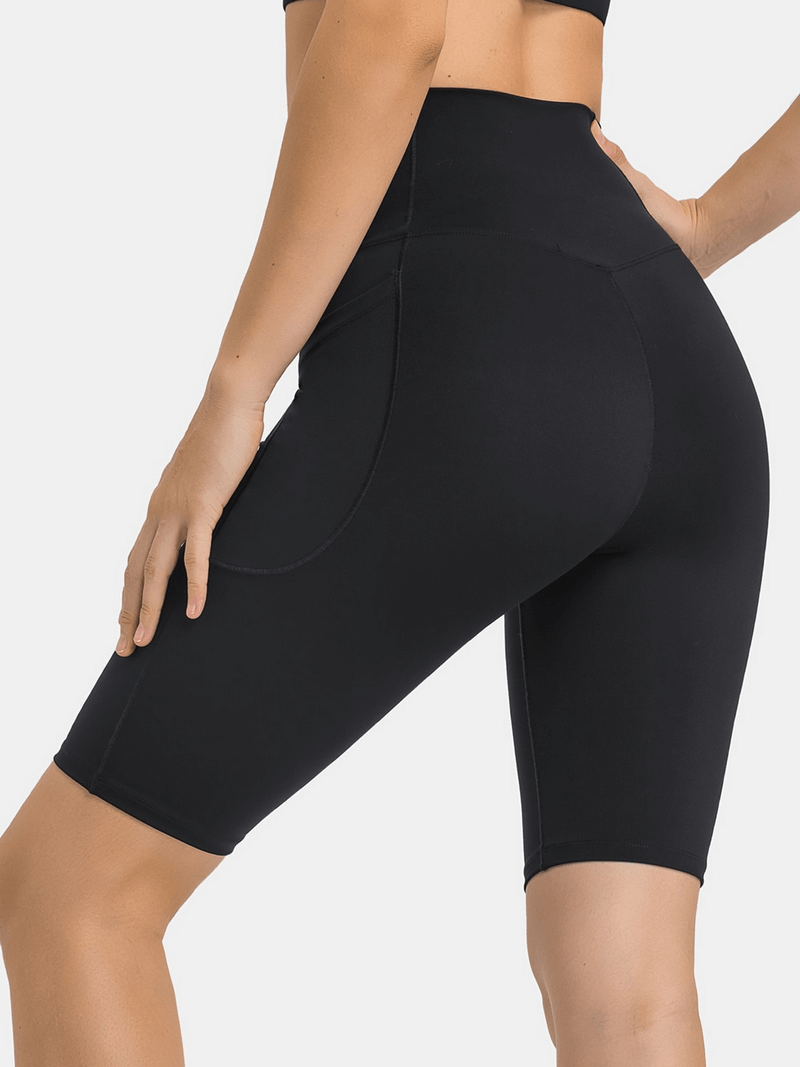 Rear view of women's black elastic yoga shorts with cross waistband and deep pockets, perfect for comfort and functionality.