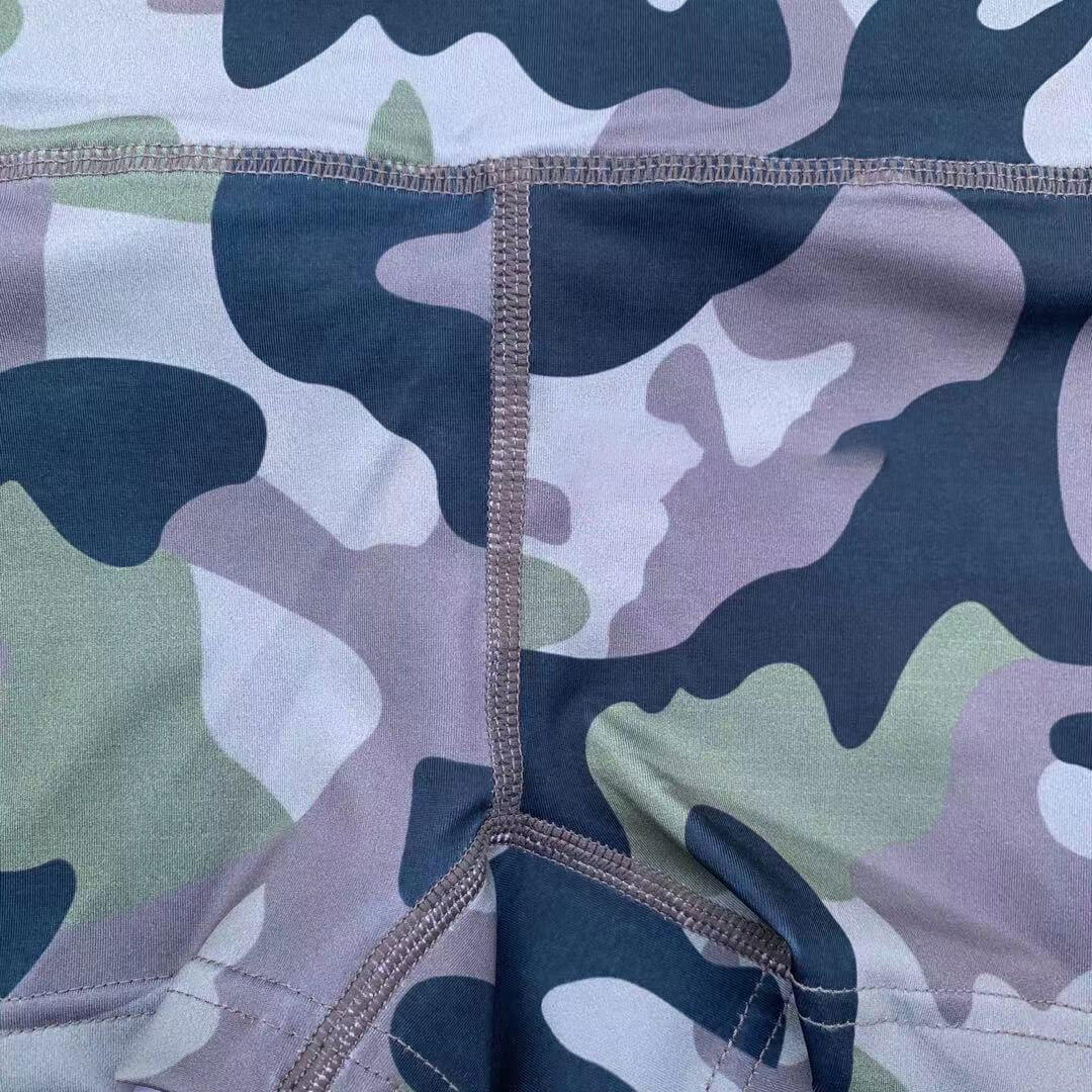 Close-up of camouflage fabric pattern on high waist shorts, showcasing durable stitching and stylish design for active wear.