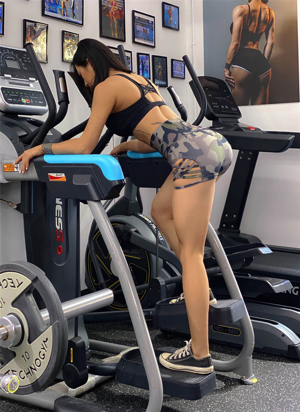 Woman wearing high waist side cross hollow shorts working out on gym equipment.