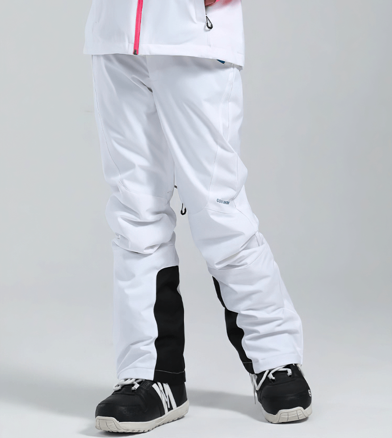 Women's high waist snow pants in white with waterproof zipper pockets, perfect for skiing and winter sports. Model wearing ski boots.
