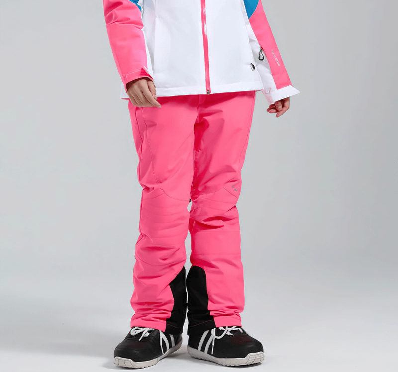 Woman wearing pink high waist snow pants with waterproof zipper pockets, ready for winter sports adventures.