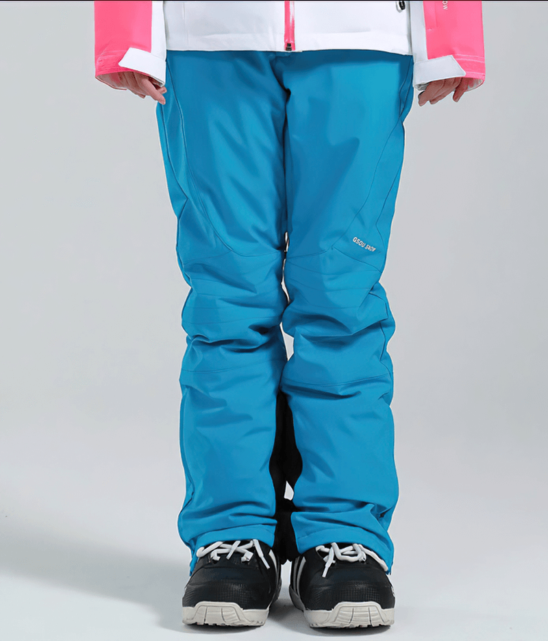 Woman wearing blue high waist snow pants with waterproof zipper pockets, perfect for skiing.