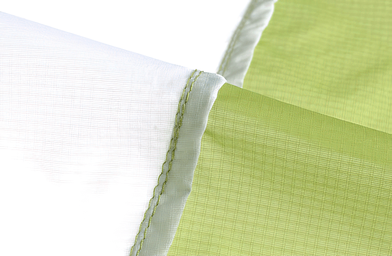 Close-up of a lightweight hiking jacket's waterproof seam demonstrating stitching and material quality in green and white colors.