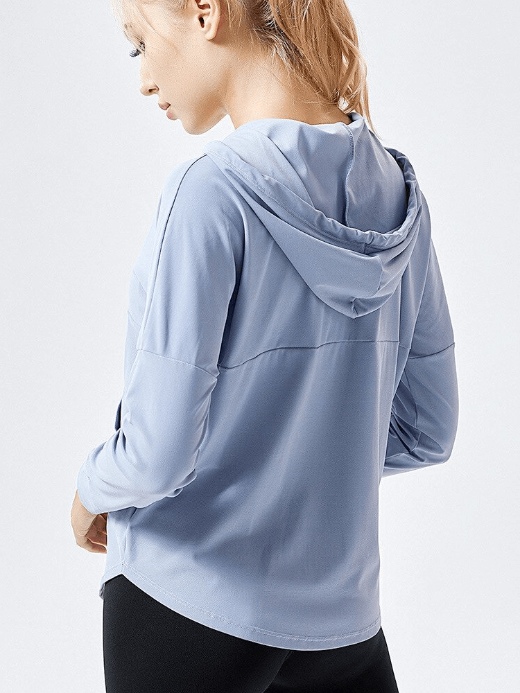 Back view of a woman wearing a light blue women's lightweight loose sports jacket with hood, perfect for yoga and running.