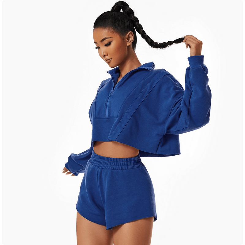Woman wearing a blue cropped sweatshirt and shorts, showcasing a stylish and comfortable athletic outfit.