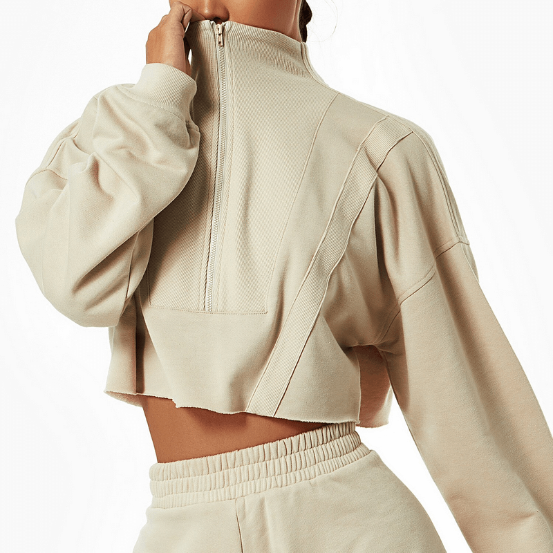 Woman wearing a beige loose cropped sweatshirt with long sleeves, perfect for yoga and workouts. Features a fashionable, breathable cotton design.