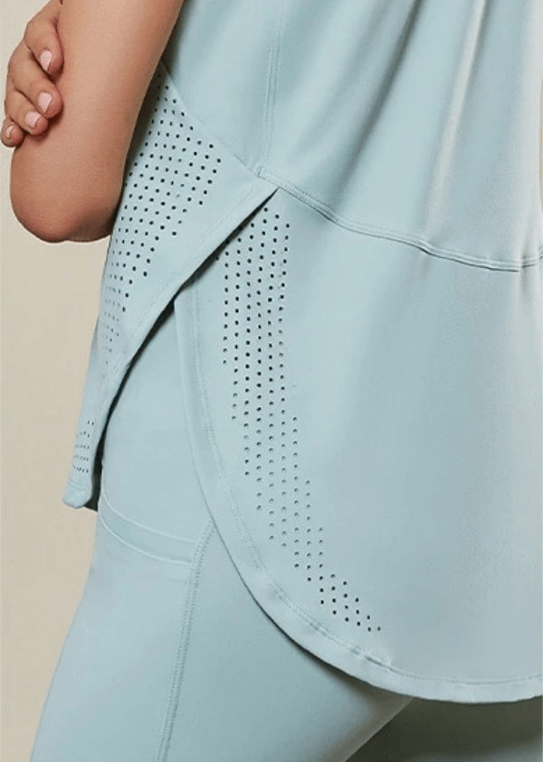 Woman wearing loose mesh sleeveless yoga top in light blue, showing breathable nylon fabric and design details, perfect for workouts.