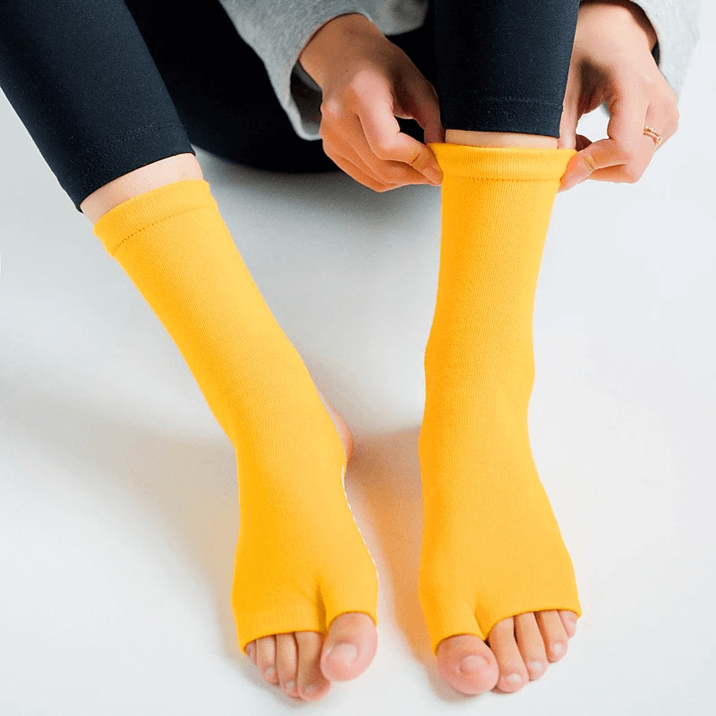 Person wearing yellow open toe yoga socks with non-slip silicone sole, ideal for improving grip and stability during yoga sessions.