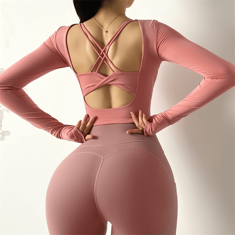 Woman wearing a pink sexy back long sleeves sports top, showcasing a stylish crisscross design, ideal for high elastic gym clothes.