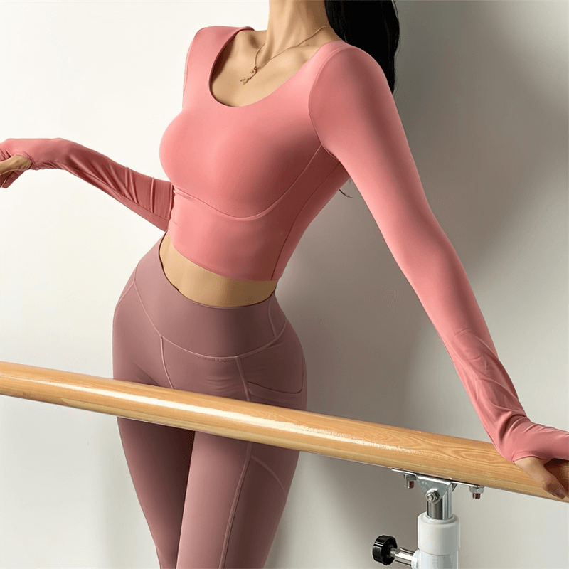 Woman wearing a pink sexy back long sleeve sports top, perfect for gym and yoga, showcasing its high elasticity and stylish design.
