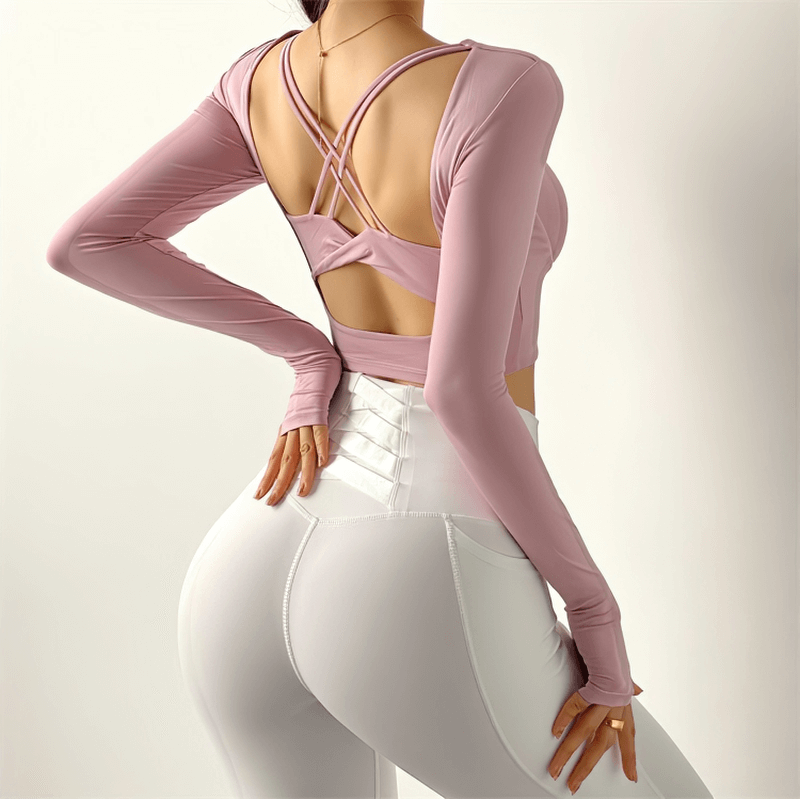 Woman in pink sexy back long sleeves sports top and white leggings, showcasing high elastic gym wear for yoga and fitness.