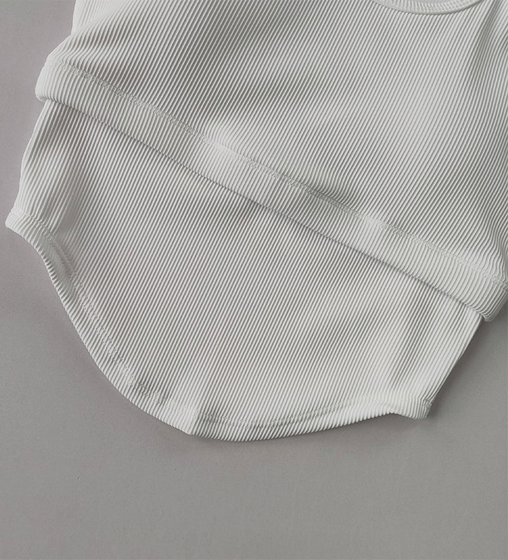 Close-up of women's white ribbed yoga top with long sleeves, showcasing breathable fabric and snug fit design.