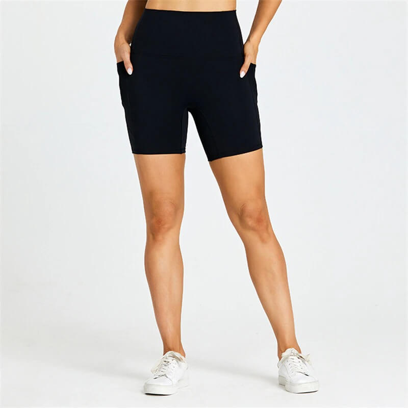Woman wearing black short tight shorts with pockets, perfect for workouts, featuring nylon and spandex blend for flexibility and comfort.