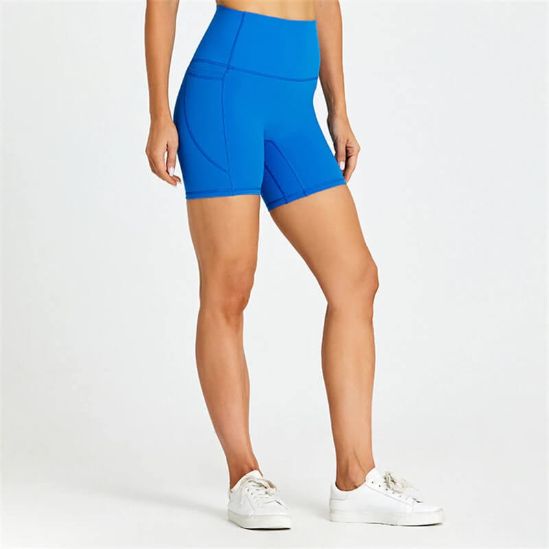 Model wearing blue women's short tight solid color shorts with pockets, ideal for workouts. Comfortable blend of nylon and spandex.