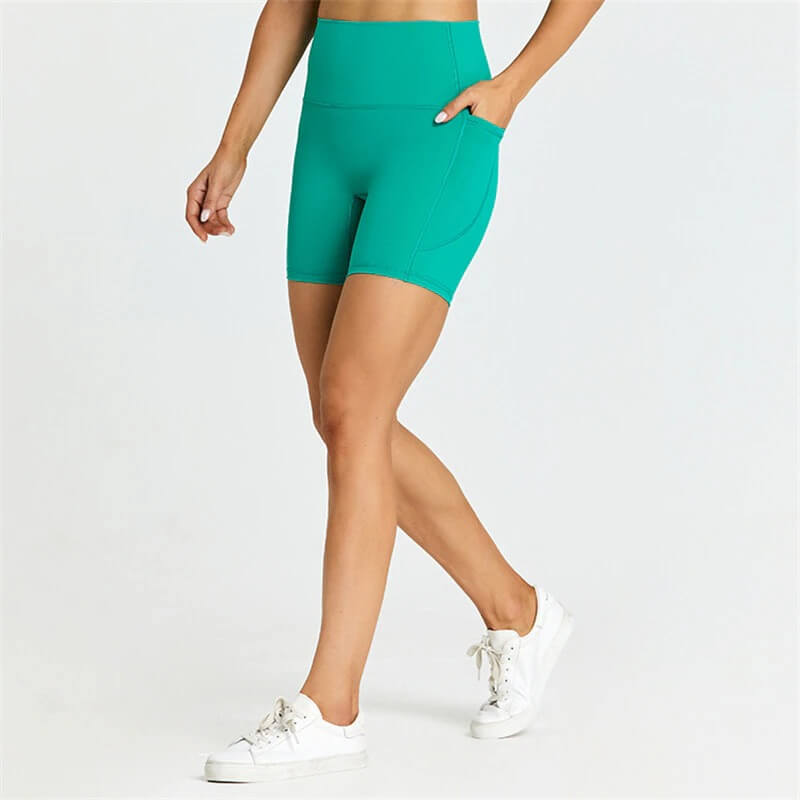 Woman wearing teal short tight solid color workout shorts with pockets, perfect for comfort and mobility.