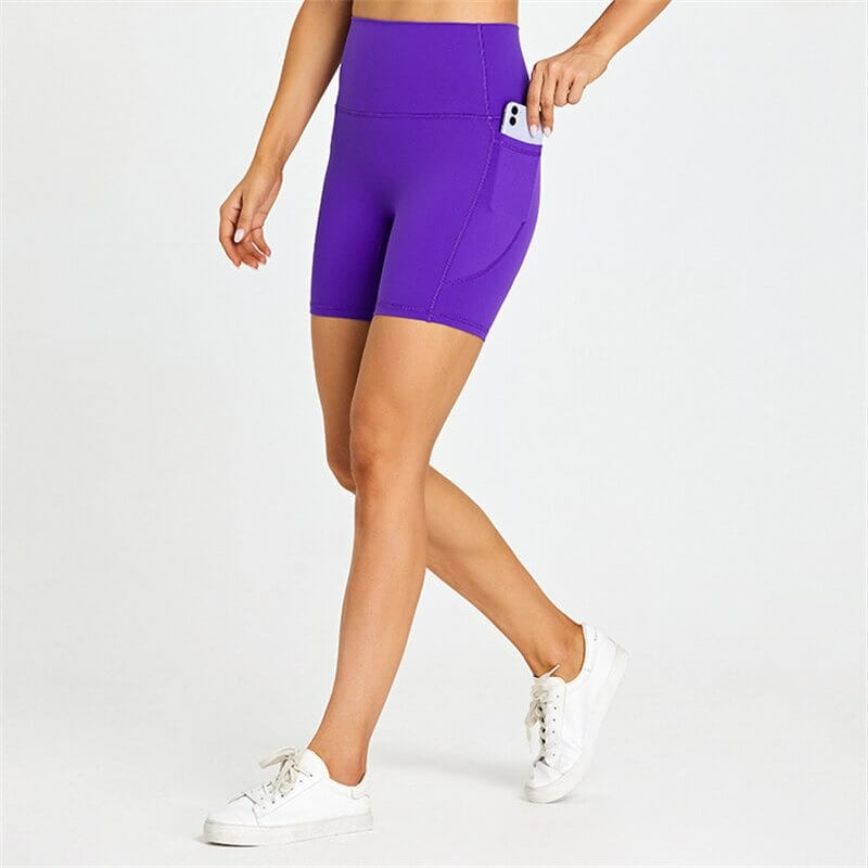 Model wearing purple women's short tight solid color shorts with pockets, showcasing comfort and mobility for workouts.