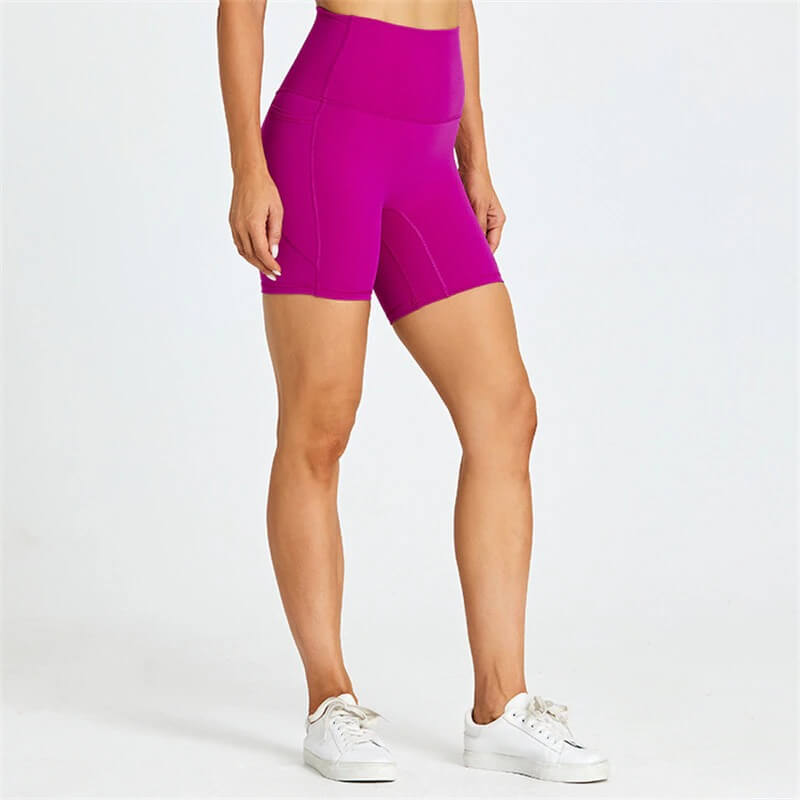 Women's solid color tight shorts with pockets in bold magenta. Perfect for workouts, offering comfort, breathability, and mobility.