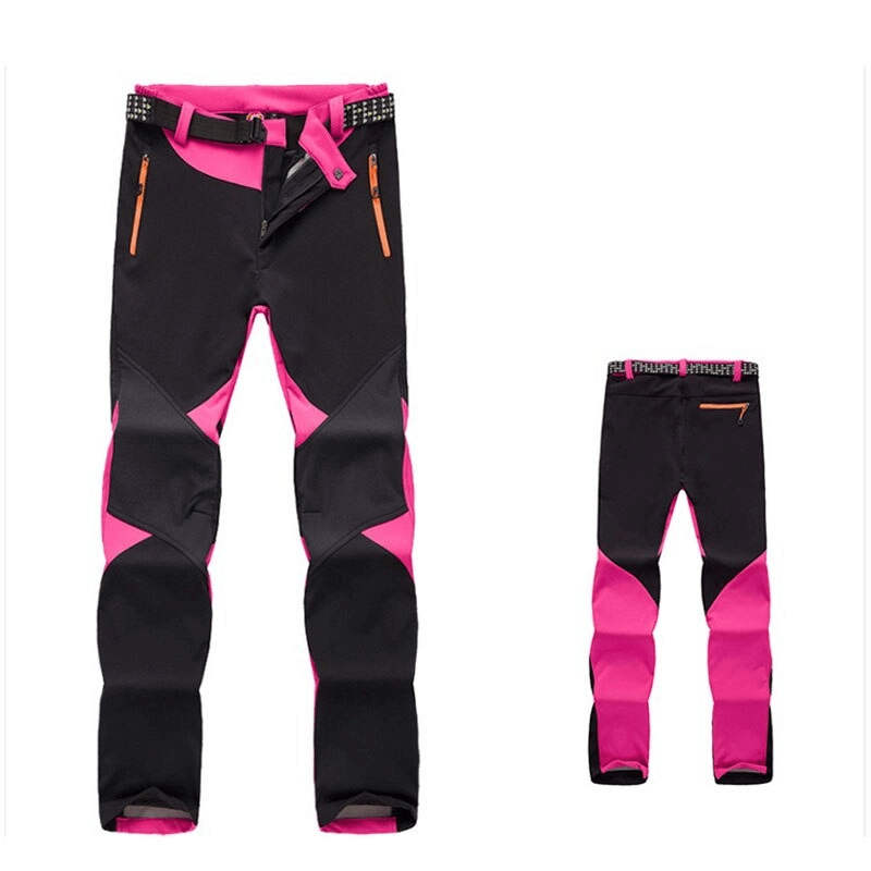 Women's pink and black softshell skiing pants with zipper fly closure, ideal for outdoor activities like skiing and trekking.