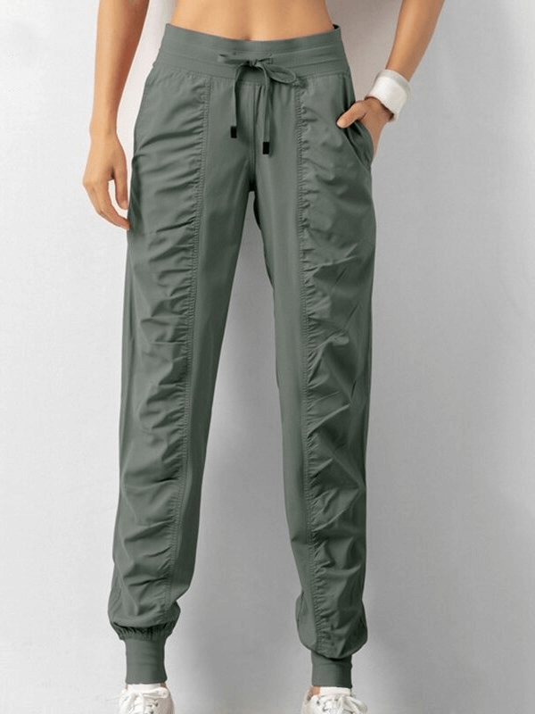 Women's sports joggers with drawstring waist, side pockets, pleated front, and cuffed hems for casual comfort and style.