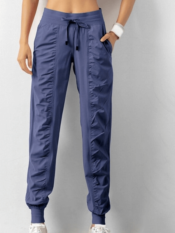 Women's sports joggers with side pockets, cuffed hems, and drawstring waist in solid color, perfect for casual comfort and style.