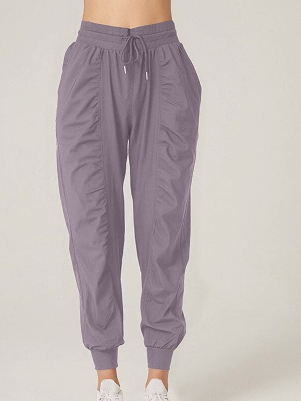 Women's sports joggers in purple with side pockets and cuffed hems; loose fit with drawstring waist for casual style. Model wearing SF0177.