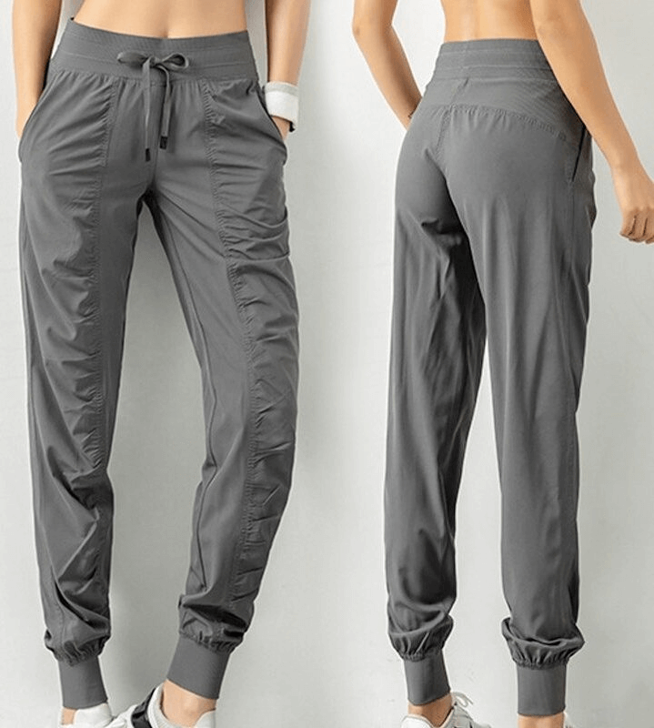 Women's sports joggers with side pockets and cuffs, solid gray color, made from polyester, featuring a loose fit and drawstring waist.