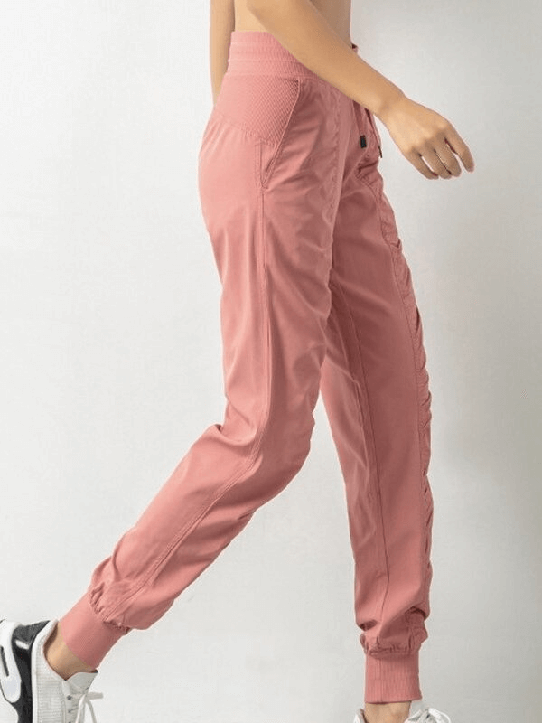 Woman wearing pink sports joggers with side pockets and cuffed hems, showcasing comfort and style for casual outings.