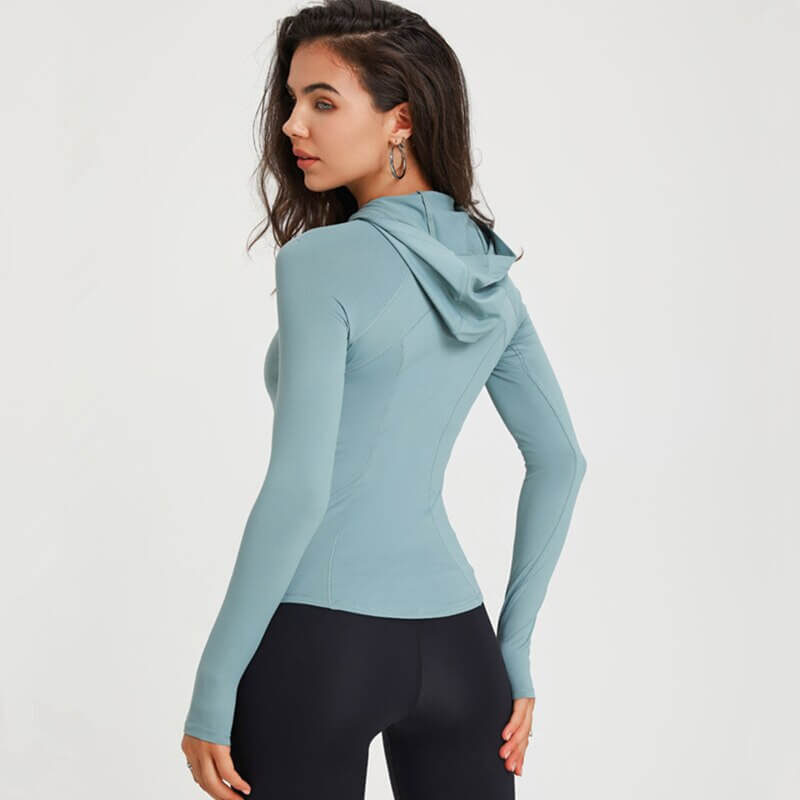 Woman wearing a light blue women's sports slim hoodie with hood, ideal for quick-dry and flexible workouts, viewed from the side.