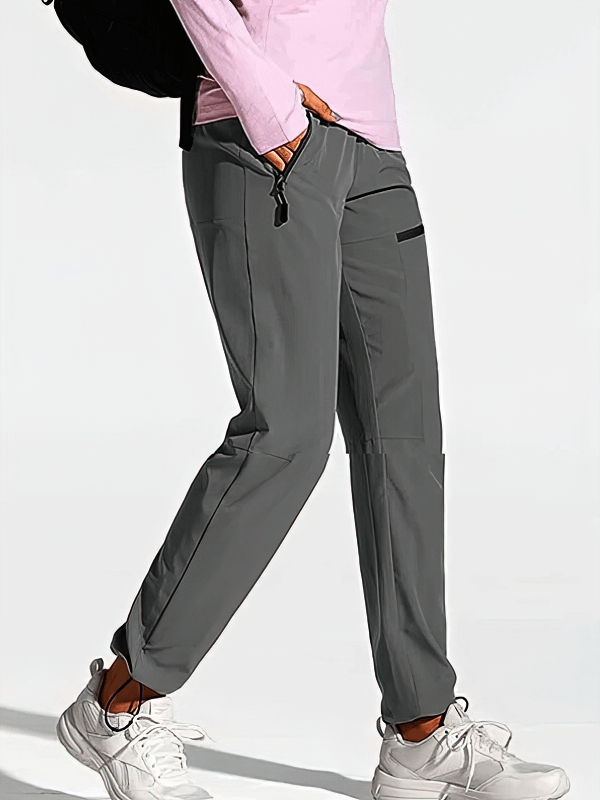 Woman wearing waterproof quick-drying hiking pants with pockets and elastic waist, ideal for outdoor activities.