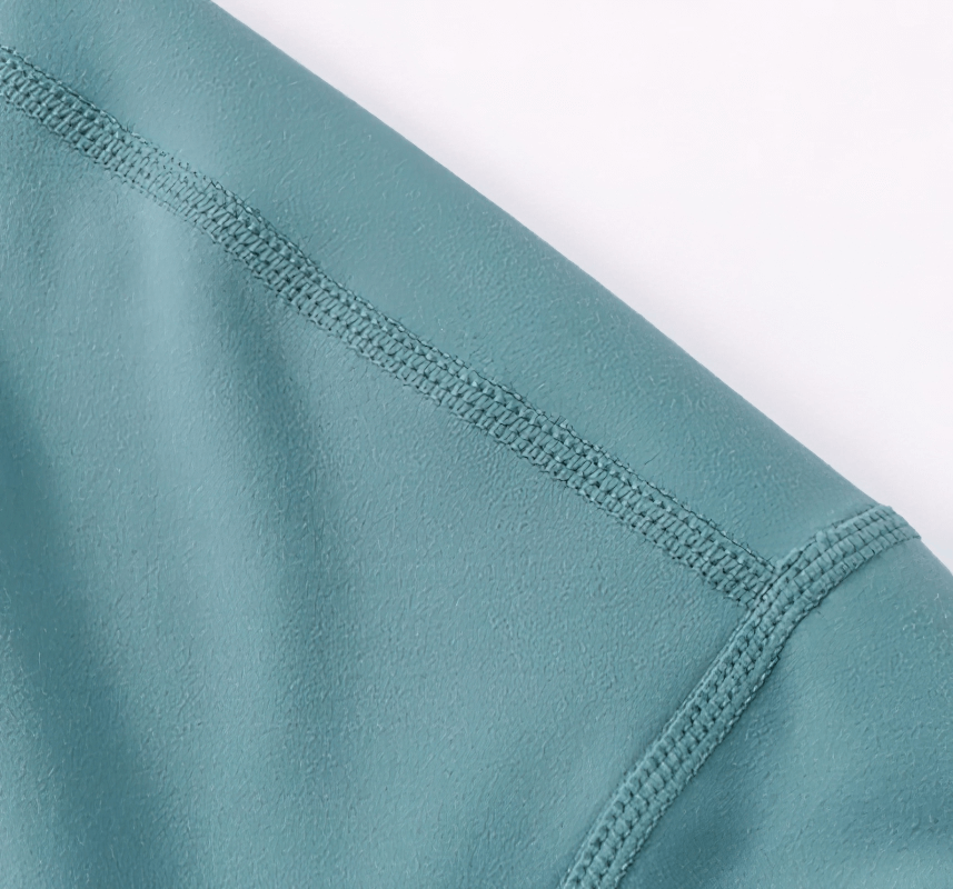 Close-up of turquoise women's sporty top showing seam detail and texture in soft, stretchy fabric.