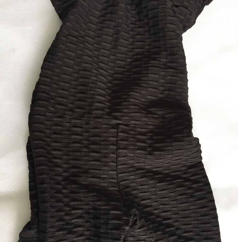Close-up of black textured women's yoga jumpsuit fabric displaying intricate design patterns and breathable, eco-friendly material.